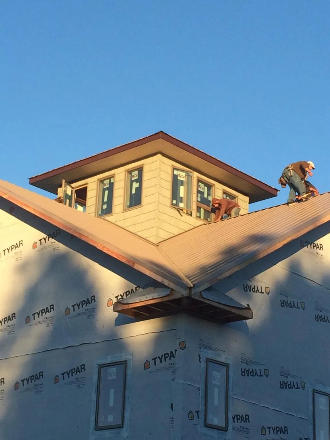 Roofers working around a rooftop cupola on a new metal roof at sunset — Roof Waterproofing in Woodside by Roofing Brothers